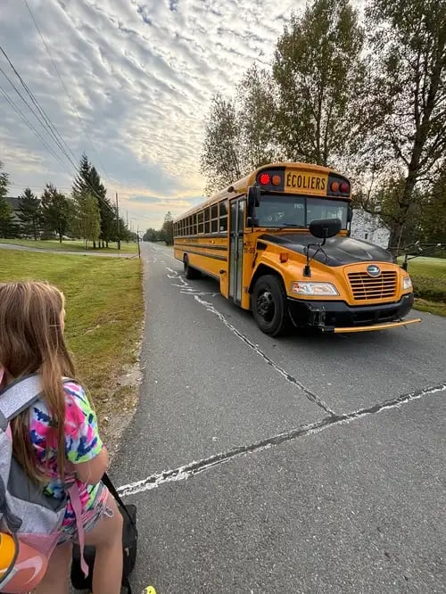 Schülerin vor einem Schulbus in den USA
